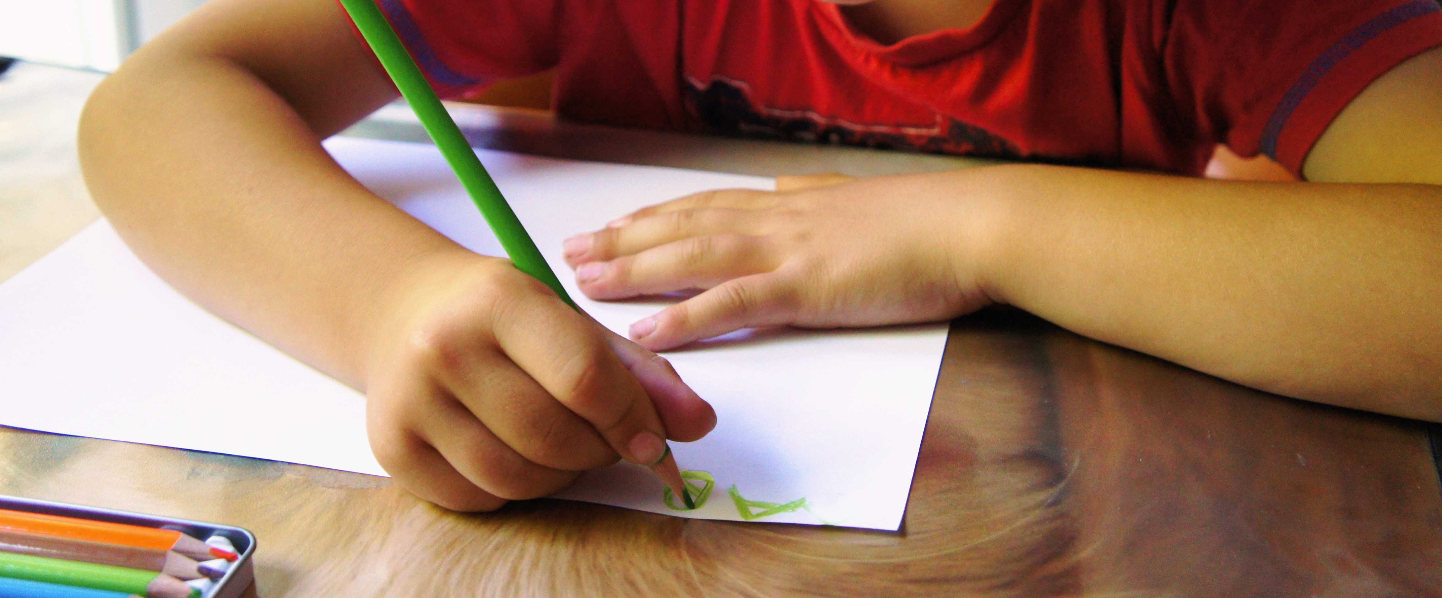 Bild: Ein Schulkind sitzt am Tisch und schreibt
